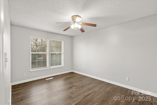 empty room featuring ceiling fan, dark hardwood / wood-style flooring, and a textured ceiling