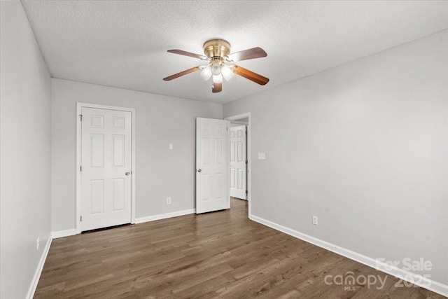 unfurnished bedroom with ceiling fan, dark hardwood / wood-style flooring, and a textured ceiling