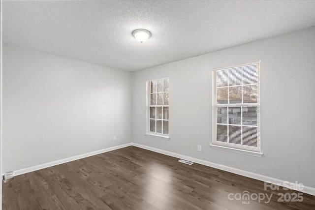 spare room featuring dark hardwood / wood-style flooring and a textured ceiling