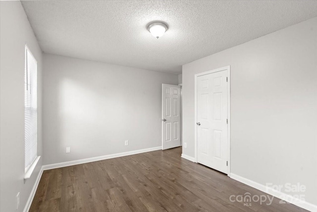 spare room featuring a textured ceiling and dark wood-type flooring