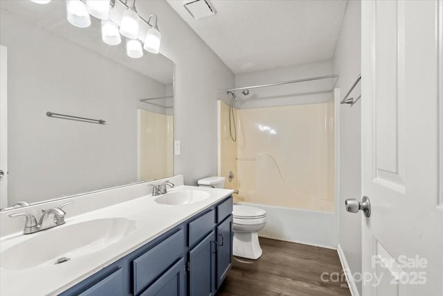 full bathroom featuring hardwood / wood-style floors, a textured ceiling, toilet, shower / washtub combination, and vanity