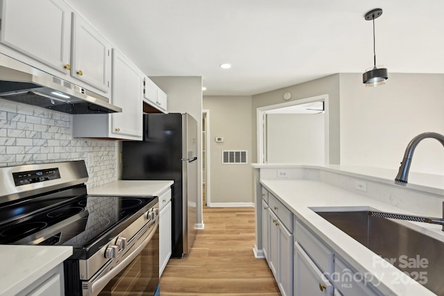 kitchen with stainless steel electric stove, white cabinets, decorative backsplash, sink, and hanging light fixtures