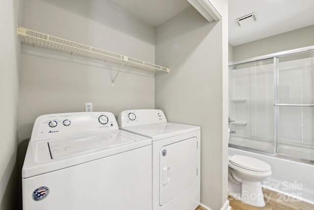 clothes washing area featuring washing machine and dryer and hardwood / wood-style floors