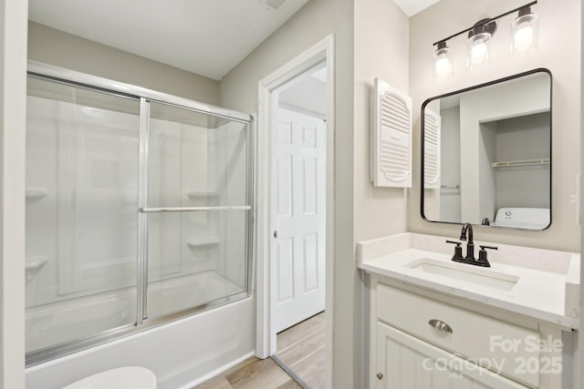 full bathroom featuring toilet, hardwood / wood-style flooring, vanity, and shower / bath combination with glass door