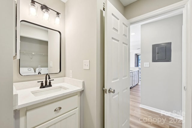 bathroom featuring electric panel, wood-type flooring, washing machine and clothes dryer, and vanity