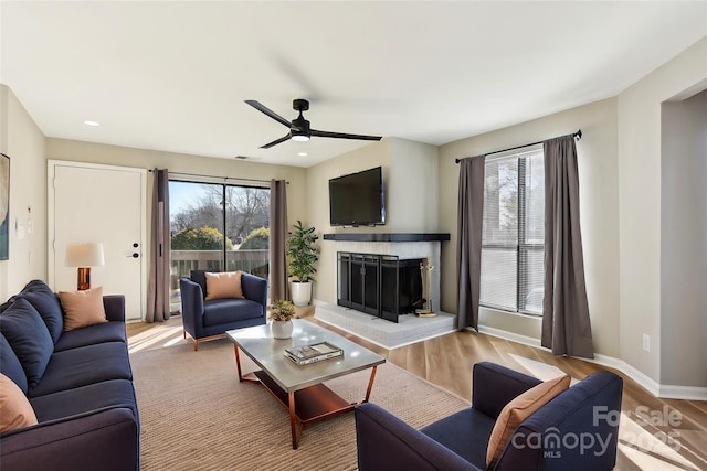 living room with light hardwood / wood-style floors, ceiling fan, and a fireplace