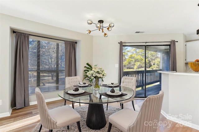 dining area featuring light wood-type flooring and a notable chandelier