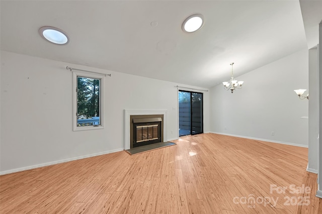 unfurnished living room featuring lofted ceiling, light wood-type flooring, and a notable chandelier