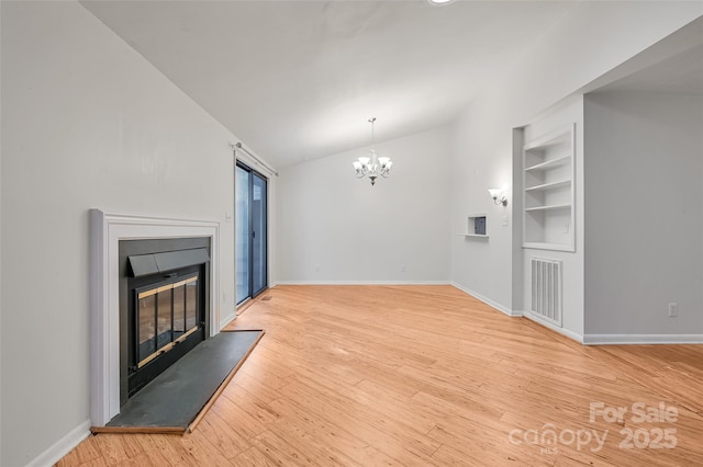 living room with lofted ceiling, an inviting chandelier, built in features, and light hardwood / wood-style floors