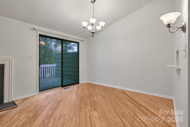 unfurnished dining area featuring a notable chandelier, vaulted ceiling, and hardwood / wood-style flooring