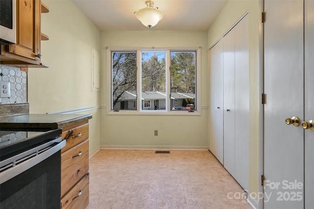 kitchen featuring electric range and backsplash