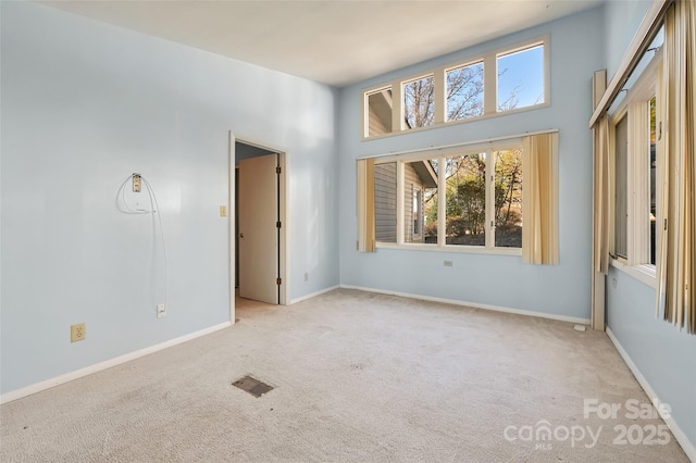 unfurnished room with a high ceiling and light colored carpet