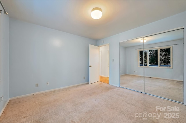 unfurnished bedroom with light colored carpet and a closet