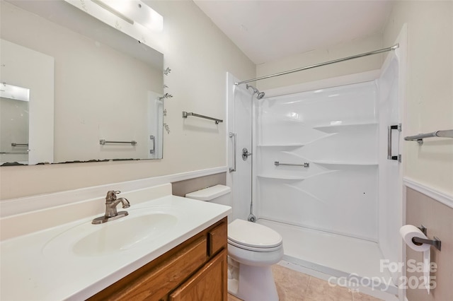 bathroom featuring toilet, a shower, vanity, and tile patterned floors