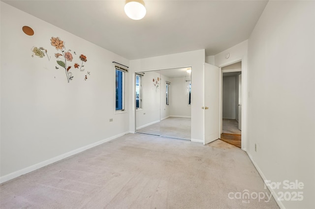 unfurnished bedroom featuring light colored carpet and a closet