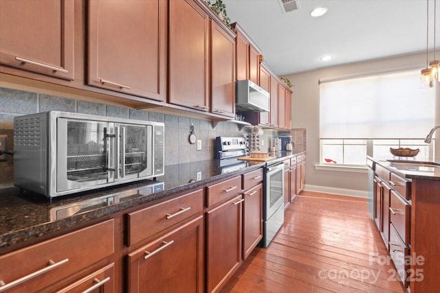 kitchen featuring sink, electric range, light hardwood / wood-style flooring, and dark stone countertops