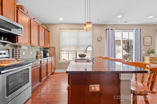 kitchen featuring backsplash, a kitchen island with sink, appliances with stainless steel finishes, and sink