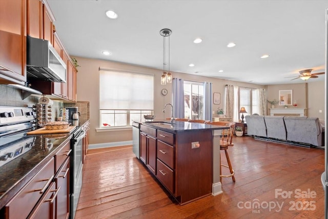 kitchen with a breakfast bar area, appliances with stainless steel finishes, a kitchen island with sink, pendant lighting, and sink