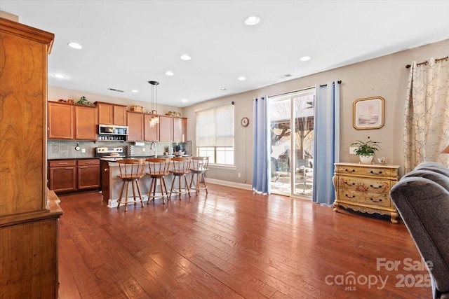 kitchen with pendant lighting, dark wood-type flooring, a breakfast bar, a center island, and stainless steel electric stove