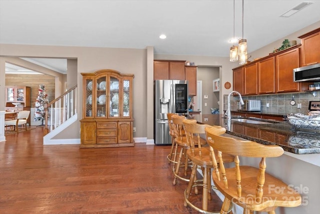 kitchen featuring sink, appliances with stainless steel finishes, dark hardwood / wood-style floors, pendant lighting, and backsplash