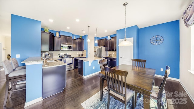 kitchen featuring dark wood-type flooring, hanging light fixtures, decorative backsplash, a kitchen island, and appliances with stainless steel finishes