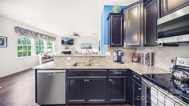 kitchen with dark wood-type flooring, sink, ceiling fan, appliances with stainless steel finishes, and light stone counters