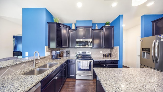 kitchen with sink, dark hardwood / wood-style floors, tasteful backsplash, light stone counters, and stainless steel appliances