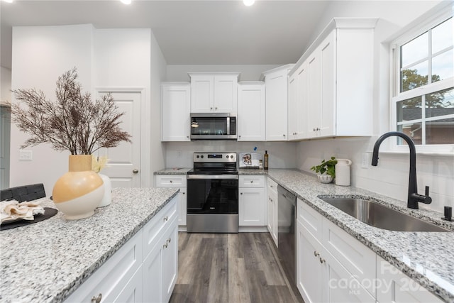 kitchen with stainless steel appliances, backsplash, white cabinets, and sink