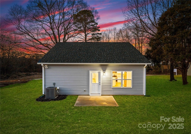 outdoor structure at dusk with central AC and a lawn