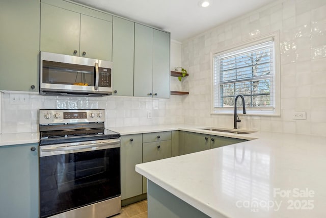 kitchen with tasteful backsplash, sink, green cabinets, and appliances with stainless steel finishes