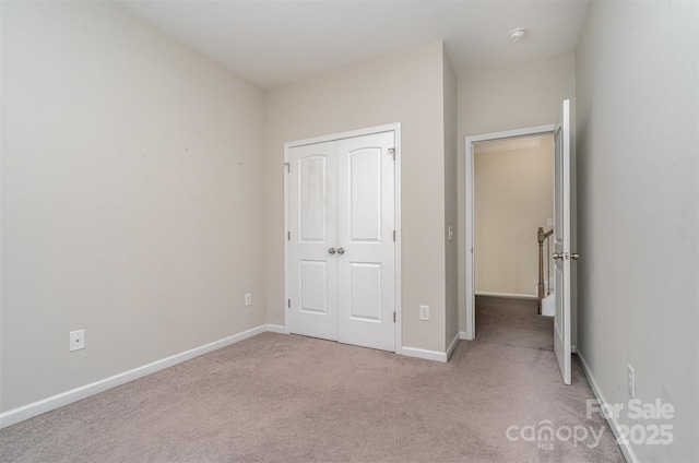 unfurnished bedroom featuring light colored carpet and a closet