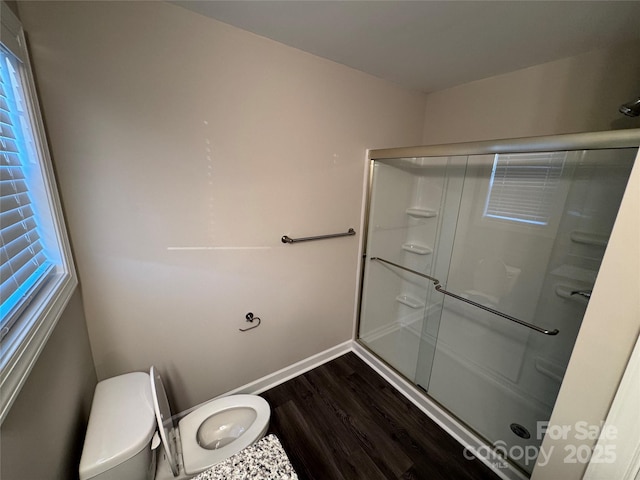 bathroom featuring hardwood / wood-style flooring, toilet, and a shower with shower door