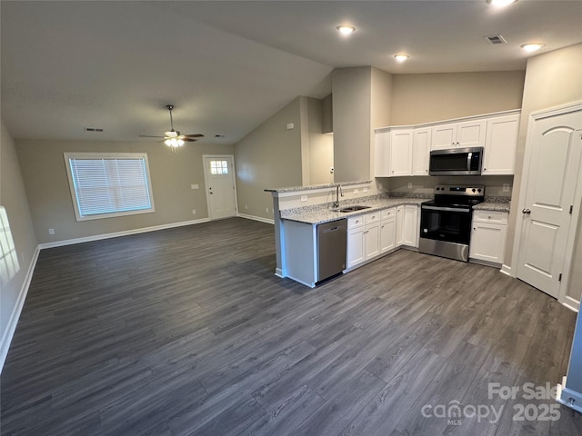 kitchen with light stone countertops, sink, kitchen peninsula, white cabinets, and appliances with stainless steel finishes