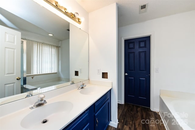 bathroom with vanity, a washtub, a textured ceiling, and wood-type flooring