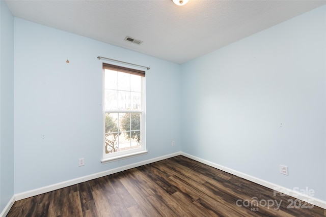 unfurnished room with a textured ceiling and dark hardwood / wood-style floors