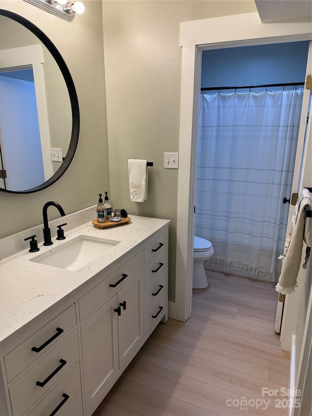 bathroom with a shower with curtain, vanity, toilet, and wood-type flooring