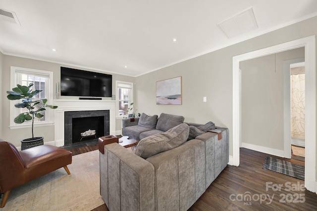 living room with plenty of natural light, a fireplace, ornamental molding, and dark hardwood / wood-style floors