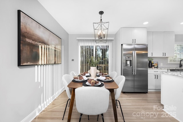 dining space featuring light wood-type flooring and a notable chandelier