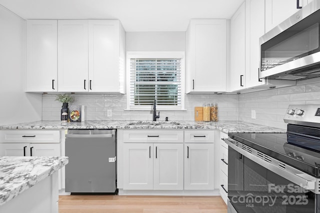 kitchen with white cabinets, light stone countertops, sink, and appliances with stainless steel finishes