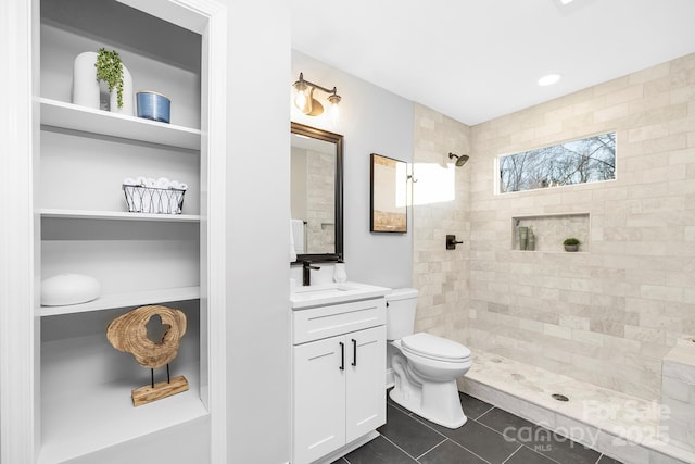 bathroom featuring a tile shower, tile patterned flooring, vanity, and toilet