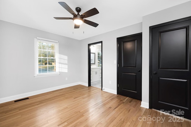 unfurnished bedroom featuring light wood-type flooring, ensuite bathroom, and ceiling fan