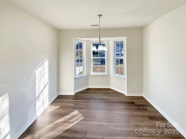 unfurnished dining area with dark hardwood / wood-style floors and a chandelier