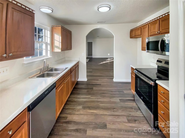 kitchen with appliances with stainless steel finishes, dark hardwood / wood-style flooring, a textured ceiling, and sink