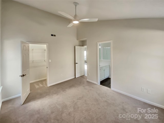 unfurnished bedroom with carpet flooring, ensuite bathroom, ceiling fan, a spacious closet, and a closet