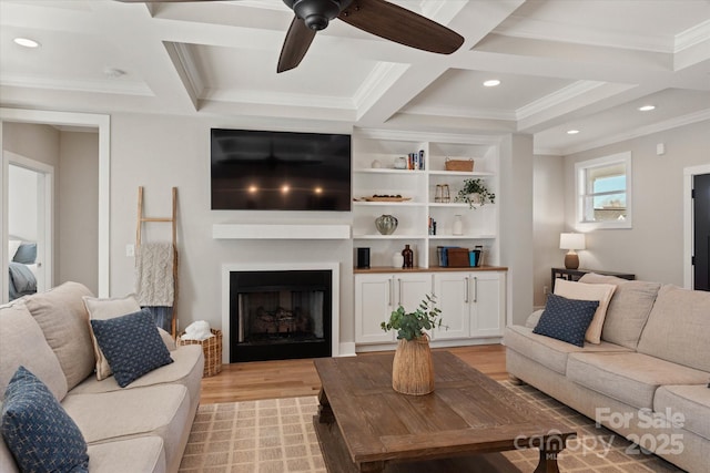 living room featuring ceiling fan, crown molding, coffered ceiling, and light hardwood / wood-style floors