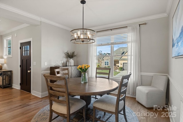 dining space featuring light hardwood / wood-style flooring, crown molding, and a chandelier