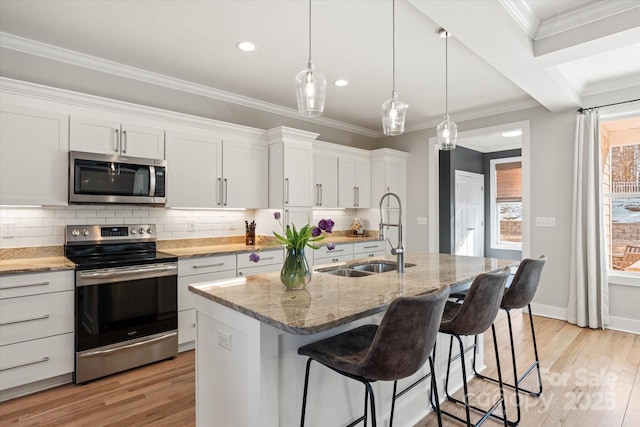 kitchen with sink, an island with sink, stainless steel appliances, and white cabinetry