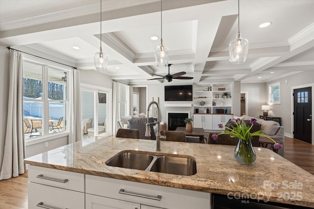 kitchen with light stone countertops, decorative light fixtures, white cabinetry, sink, and coffered ceiling