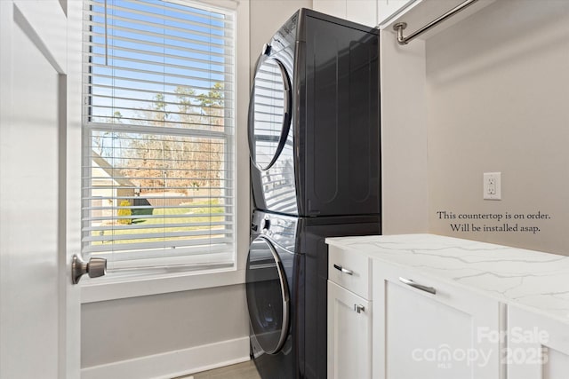 laundry area with stacked washer and dryer and cabinets