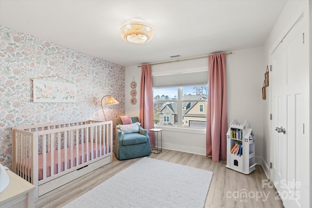 bedroom featuring a nursery area and wood-type flooring